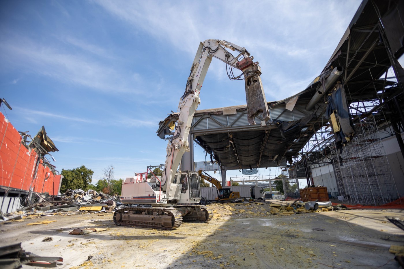Pelle de démolition à longue portée déconstruisant une toiture industrielle