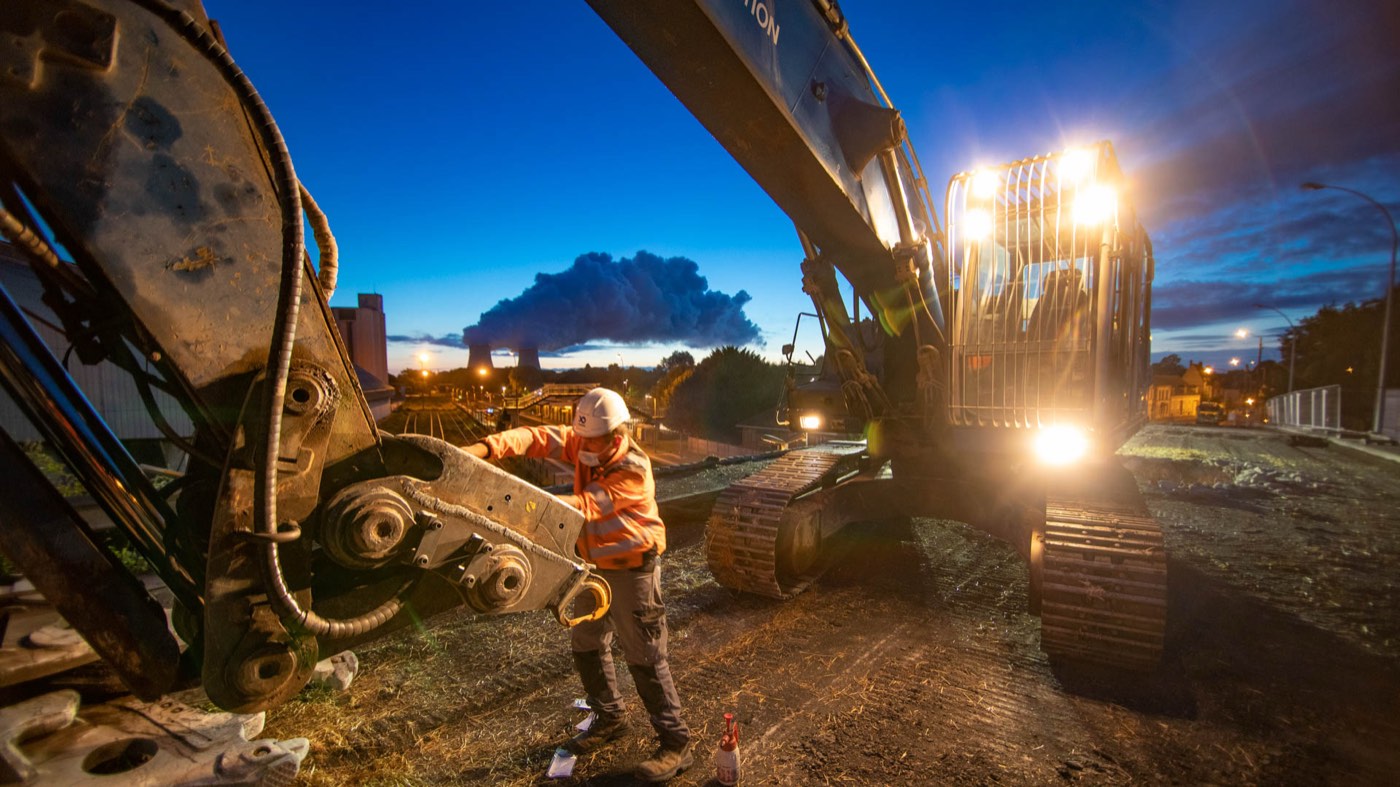 Opérateur devant la pelle de démolition au crépuscule